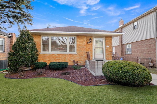 view of front of house with central AC and a front yard