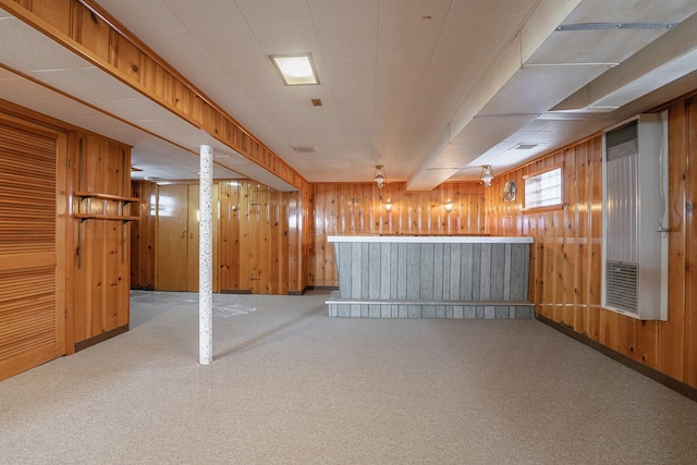 basement with light carpet, bar area, and wooden walls