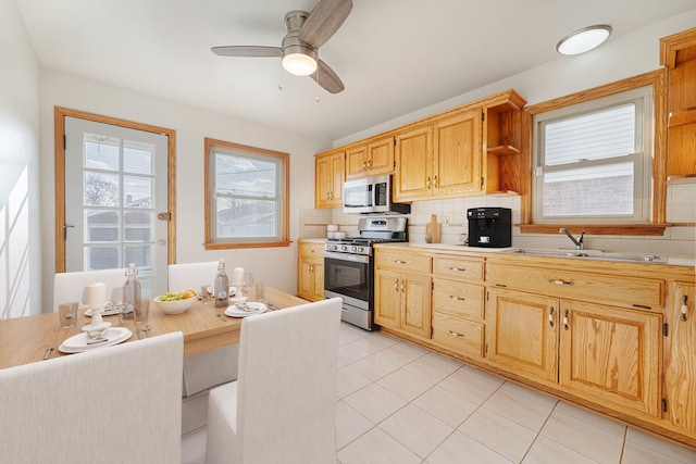 kitchen with light tile patterned flooring, tasteful backsplash, sink, ceiling fan, and stainless steel appliances