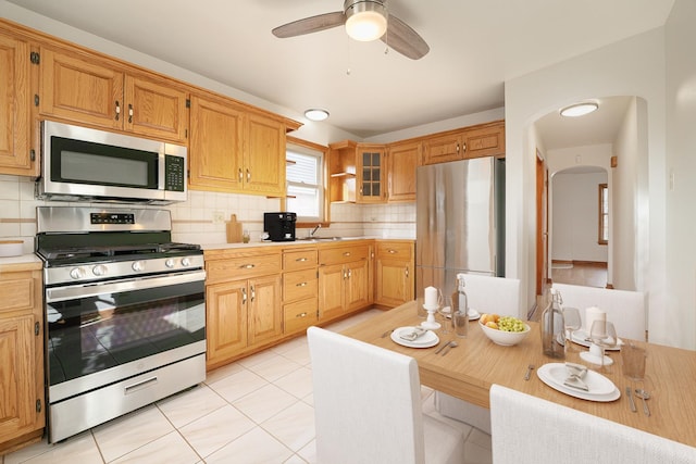 kitchen with light tile patterned flooring, appliances with stainless steel finishes, backsplash, and ceiling fan