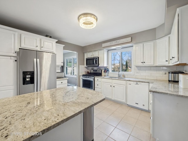 kitchen with light stone countertops, white cabinetry, appliances with stainless steel finishes, and plenty of natural light