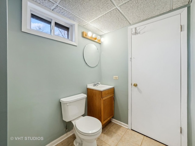 bathroom featuring vanity, toilet, tile patterned flooring, and a drop ceiling