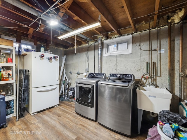 clothes washing area with sink, light hardwood / wood-style flooring, and washer and dryer