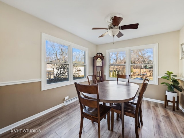 dining space featuring light wood-type flooring, ceiling fan, and a baseboard heating unit