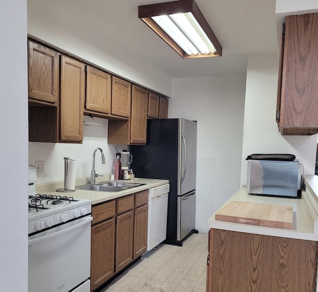 kitchen with white appliances, light countertops, a sink, and light floors