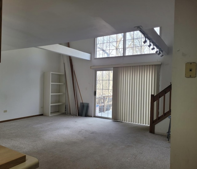 unfurnished living room featuring a towering ceiling, carpet, and stairway