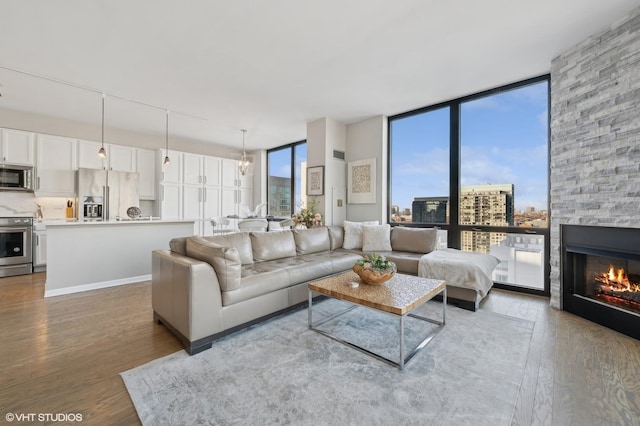 living room featuring hardwood / wood-style flooring, expansive windows, and a stone fireplace