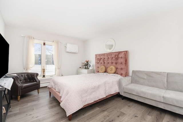 bedroom with a baseboard radiator and hardwood / wood-style floors