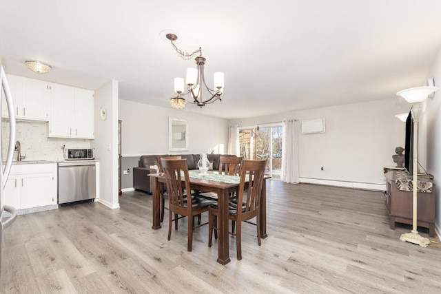 dining area featuring sink, light hardwood / wood-style flooring, a chandelier, and a baseboard heating unit