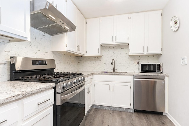 kitchen with sink, stainless steel appliances, white cabinetry, and light hardwood / wood-style flooring