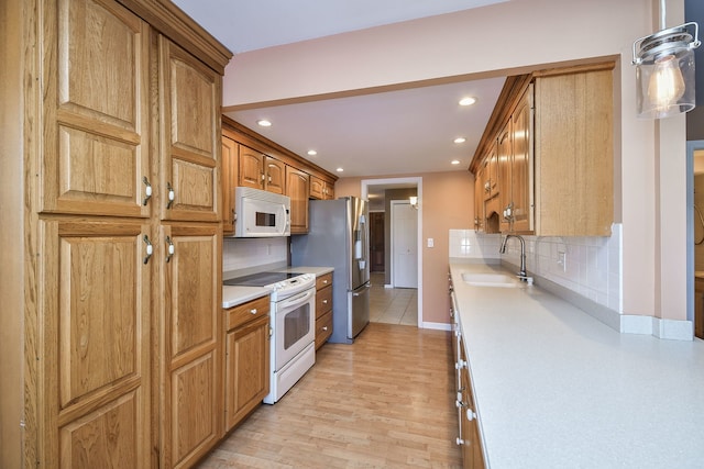 kitchen with decorative backsplash, white appliances, light countertops, and a sink