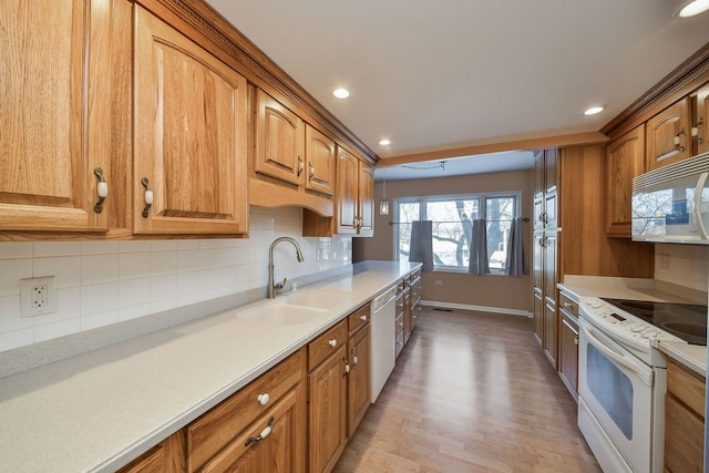 kitchen with white appliances, brown cabinetry, light countertops, and a sink