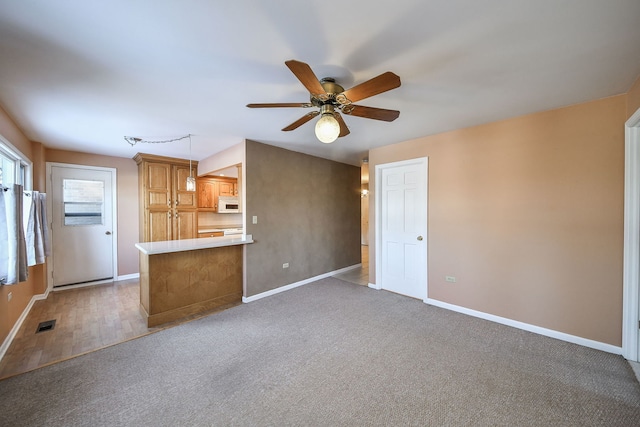 unfurnished living room with light carpet, baseboards, visible vents, and ceiling fan