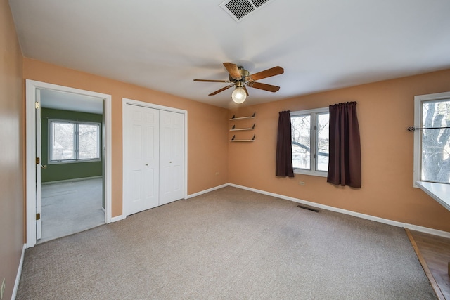 unfurnished bedroom featuring visible vents, multiple windows, baseboards, and carpet floors