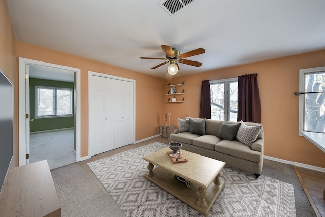 living room featuring carpet, a ceiling fan, visible vents, and baseboards