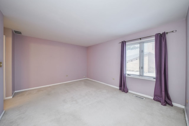 empty room with baseboards, visible vents, and light carpet