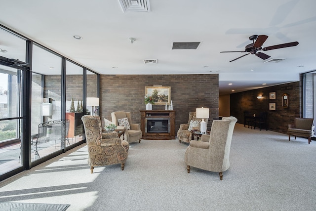 living area featuring visible vents, carpet floors, a glass covered fireplace, and a ceiling fan