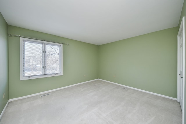 empty room with baseboards, light carpet, and visible vents