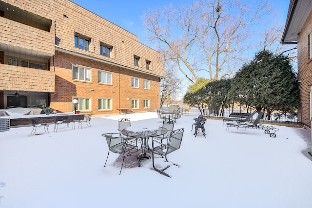 snowy yard featuring outdoor dining area and fence