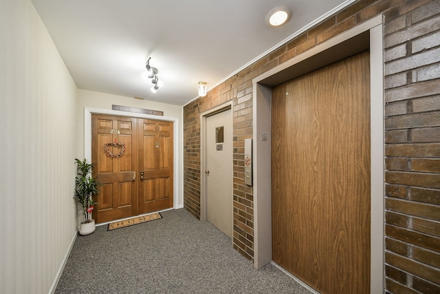 interior space featuring elevator, brick wall, and carpet