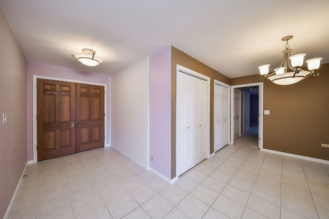 entryway with light tile patterned floors, baseboards, and a chandelier