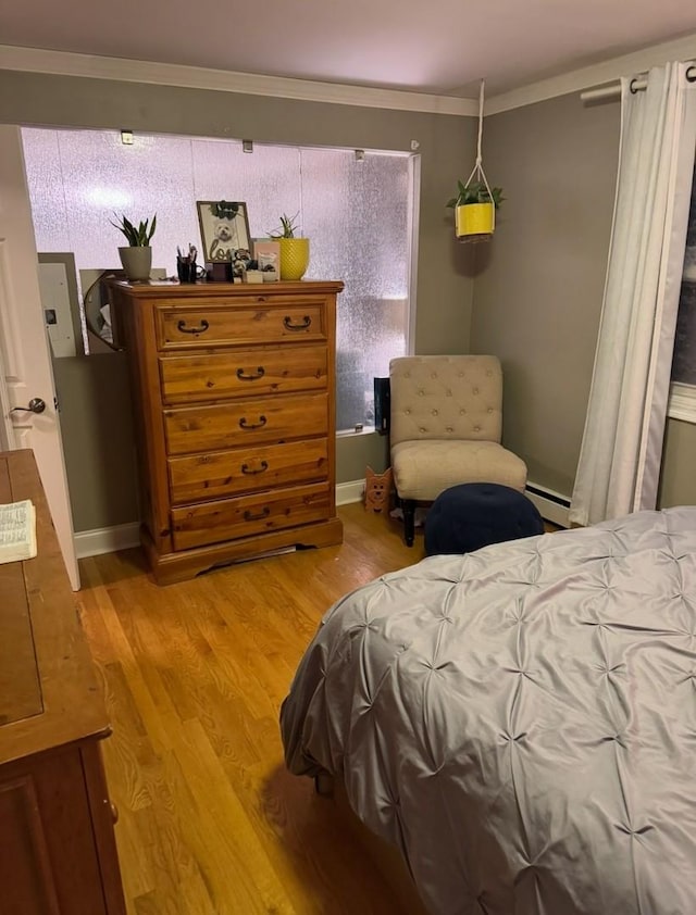 bedroom with light wood-type flooring, ornamental molding, and a baseboard radiator