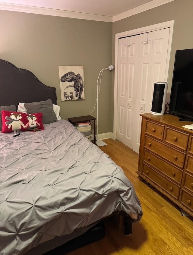 bedroom with a closet, light wood-type flooring, and ornamental molding