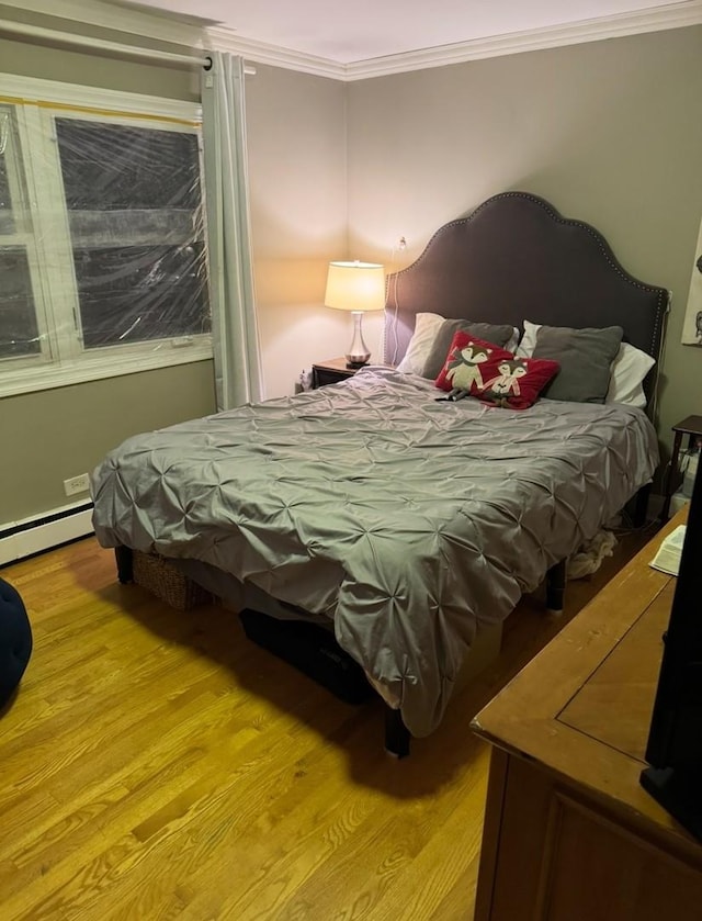 bedroom with baseboard heating, light hardwood / wood-style flooring, and crown molding