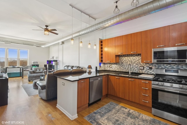 kitchen with kitchen peninsula, ceiling fan, appliances with stainless steel finishes, light hardwood / wood-style flooring, and sink