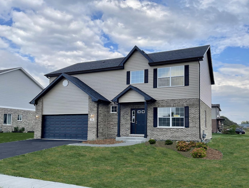 view of front of property with brick siding, a garage, driveway, and a front yard
