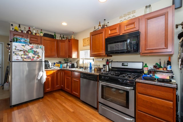 kitchen with stainless steel appliances, light hardwood / wood-style floors, and sink