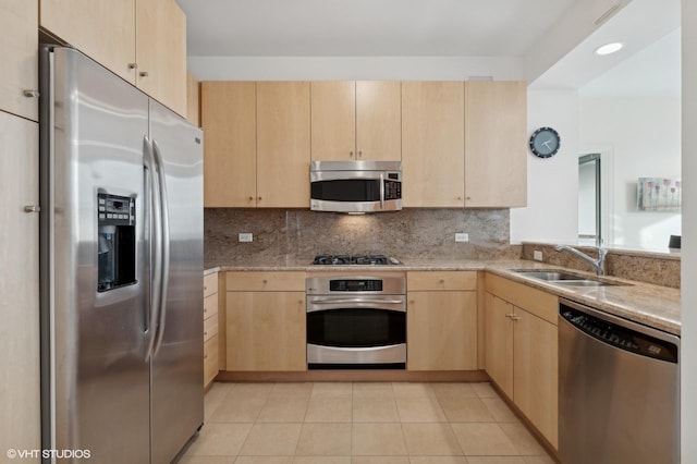 kitchen featuring stainless steel appliances, light brown cabinetry, tasteful backsplash, and sink