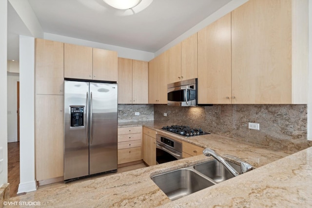 kitchen with appliances with stainless steel finishes, light brown cabinetry, and sink