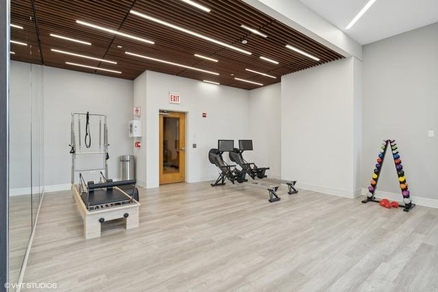 workout room featuring a towering ceiling and light wood-type flooring