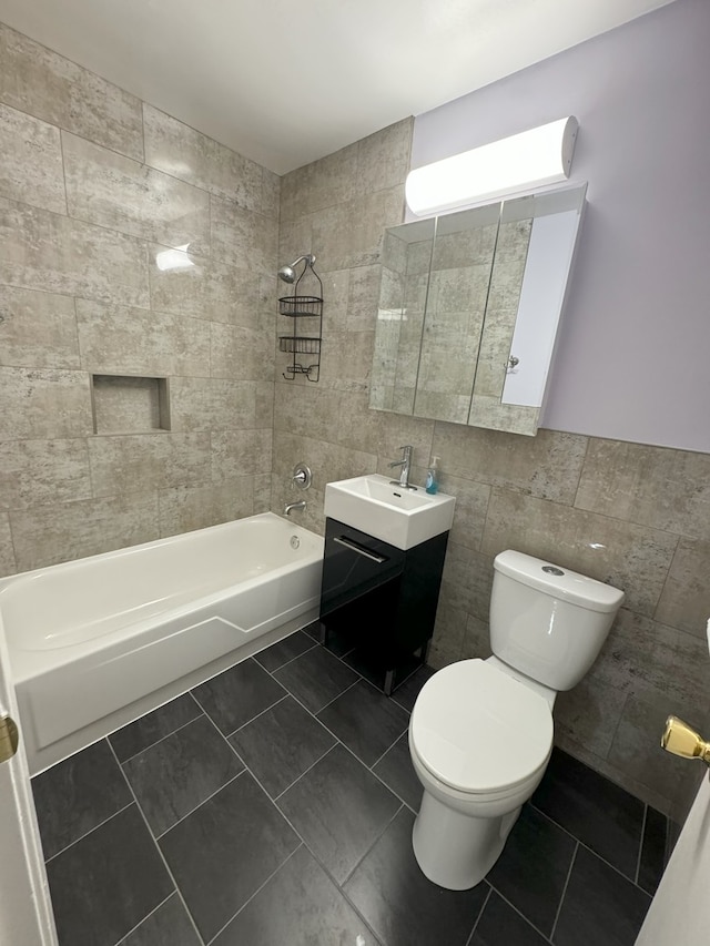 full bath with tile walls, toilet, tub / shower combination, vanity, and tile patterned flooring