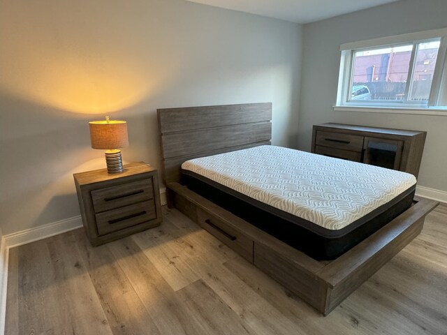 bedroom featuring light wood finished floors and baseboards