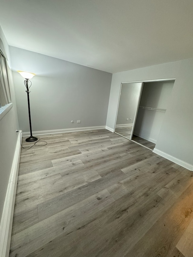 unfurnished bedroom featuring a closet, light wood-style flooring, and baseboards