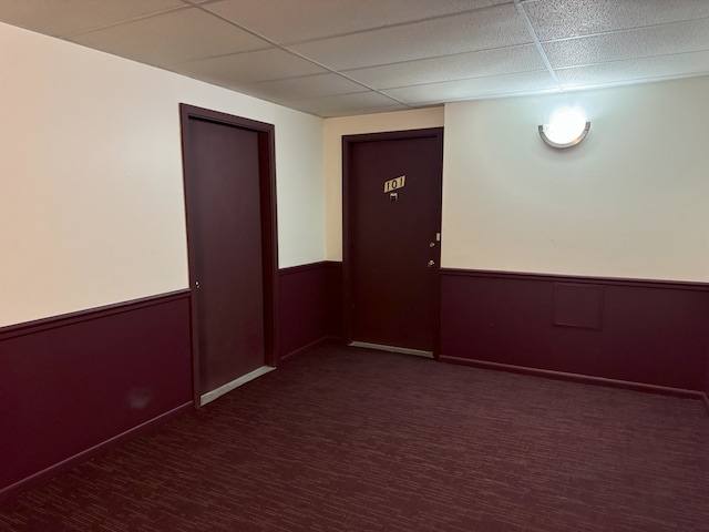 unfurnished room featuring a drop ceiling and wainscoting