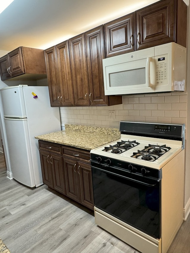 kitchen with white appliances, light wood-type flooring, dark brown cabinetry, and decorative backsplash