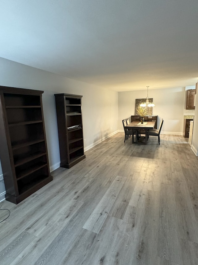 dining area featuring light wood-style flooring, baseboards, and a chandelier