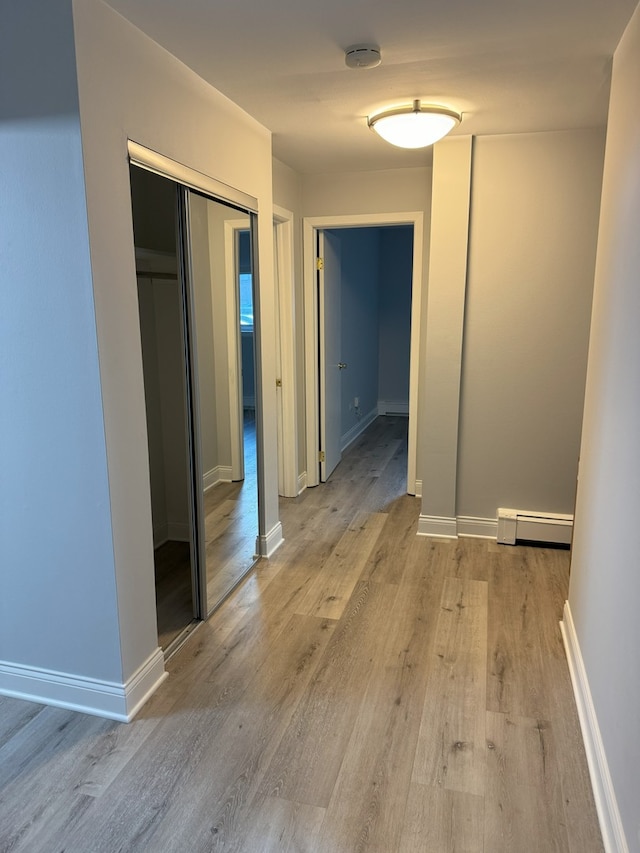 hall with light wood finished floors, baseboards, and a baseboard heating unit