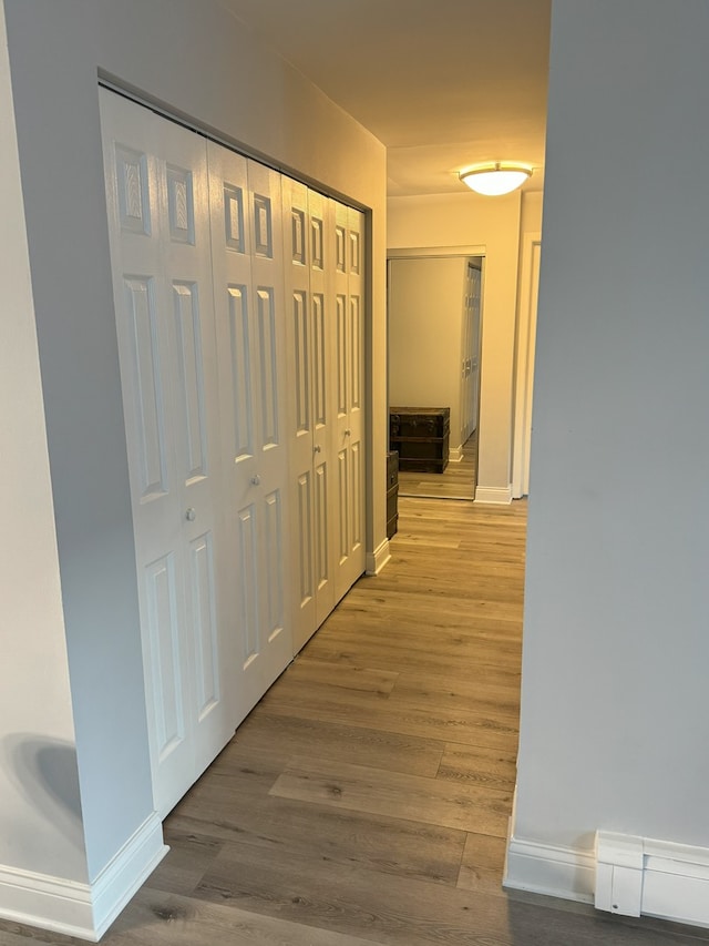 hallway featuring baseboard heating, light wood-style flooring, and baseboards