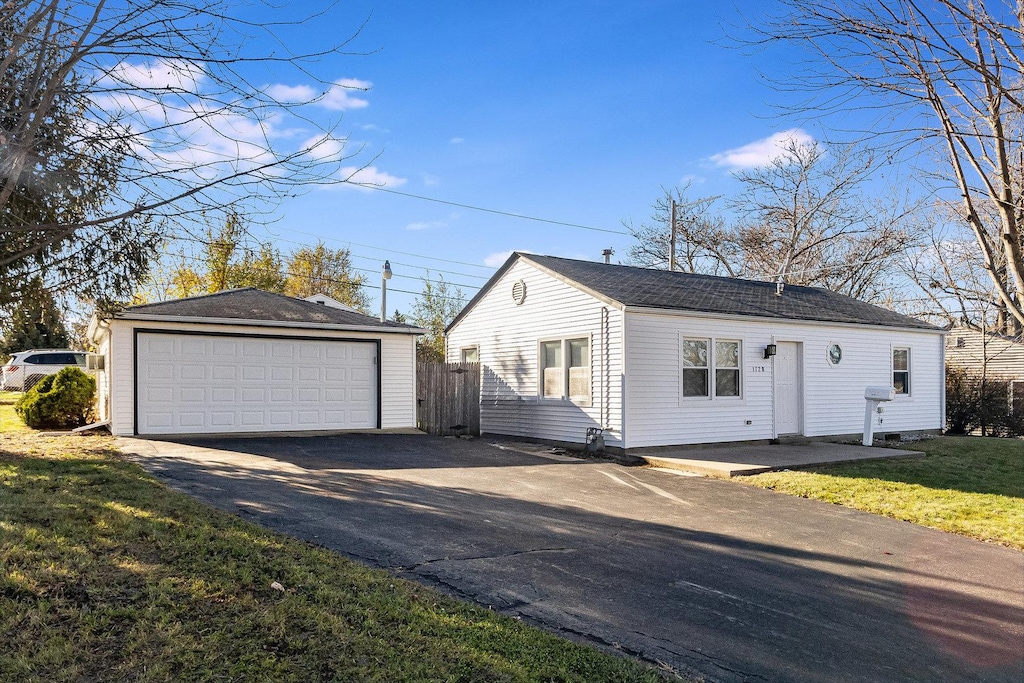 single story home featuring a front yard, a garage, and an outdoor structure