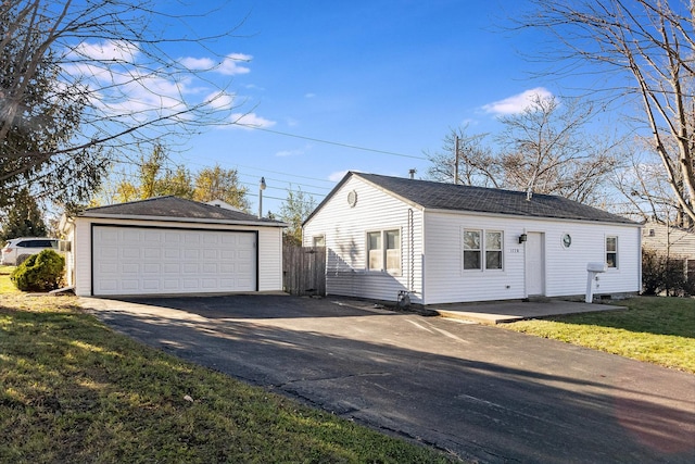 single story home featuring a front yard, a garage, and an outdoor structure