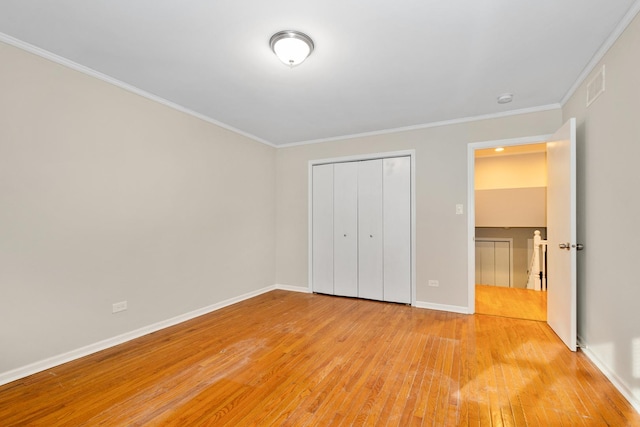 unfurnished bedroom with ornamental molding, a closet, and light hardwood / wood-style flooring