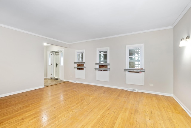 empty room featuring ornamental molding, a wealth of natural light, and light hardwood / wood-style flooring