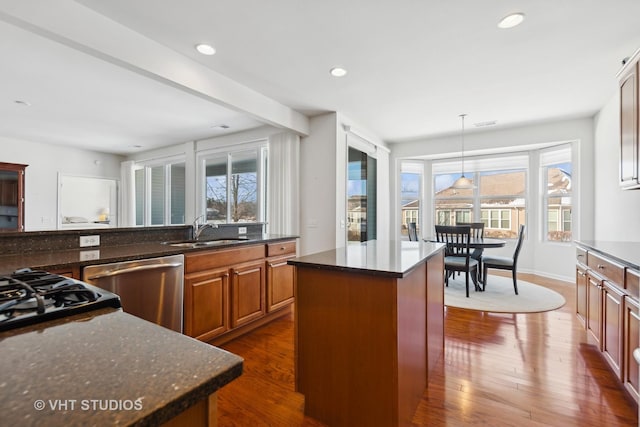 kitchen with dark wood-type flooring, sink, dishwasher, a kitchen island, and pendant lighting