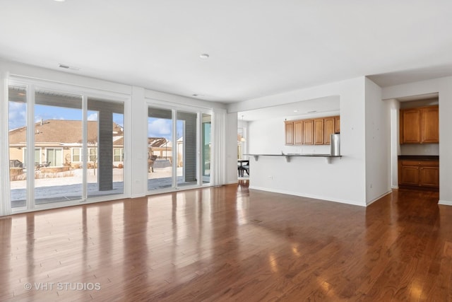 unfurnished living room featuring a healthy amount of sunlight and dark hardwood / wood-style flooring