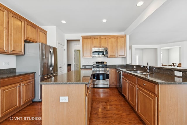 kitchen featuring a kitchen island, appliances with stainless steel finishes, sink, dark stone countertops, and dark wood-type flooring