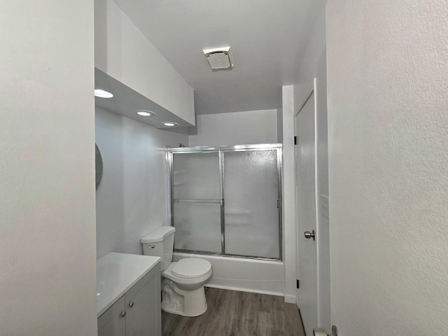 full bathroom featuring vanity, toilet, combined bath / shower with glass door, and hardwood / wood-style floors